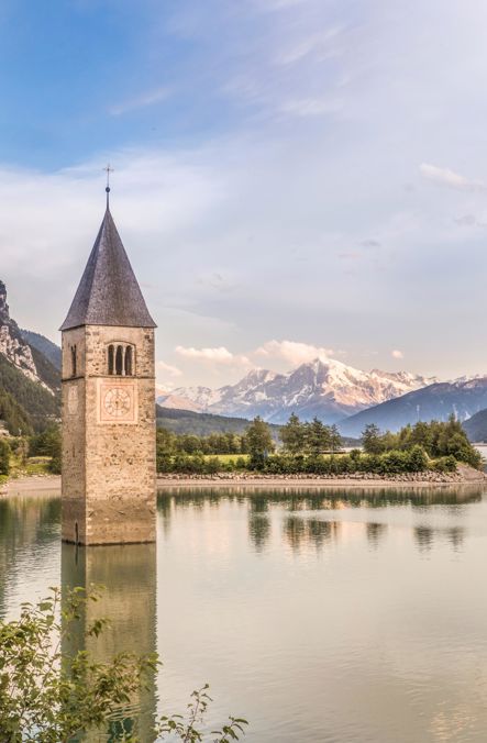 Campanile nel Lago di Resia davanti alle montagne innevate