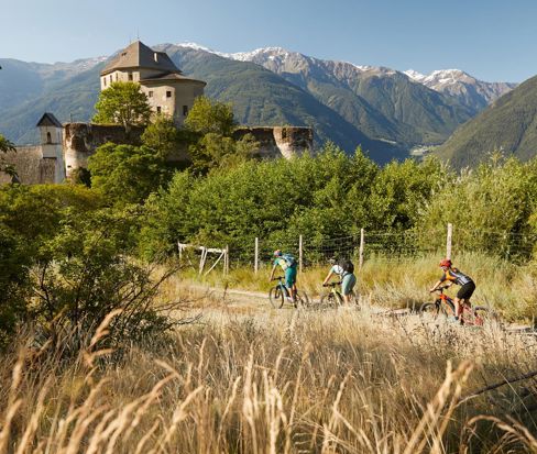 Mountain biker sotto un castello con le montagne dell'Alto Adige