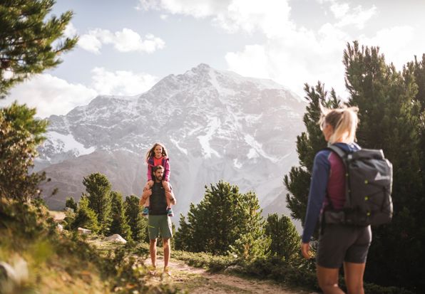 Familie beim Wandern mit Blick auf schneebedeckte Berge
