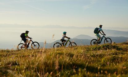E-biker su un prato di montagna al tramonto vicino a Merano
