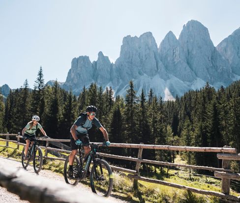 Ciclisti su una pista ciclabile davanti alle cime dolomitiche